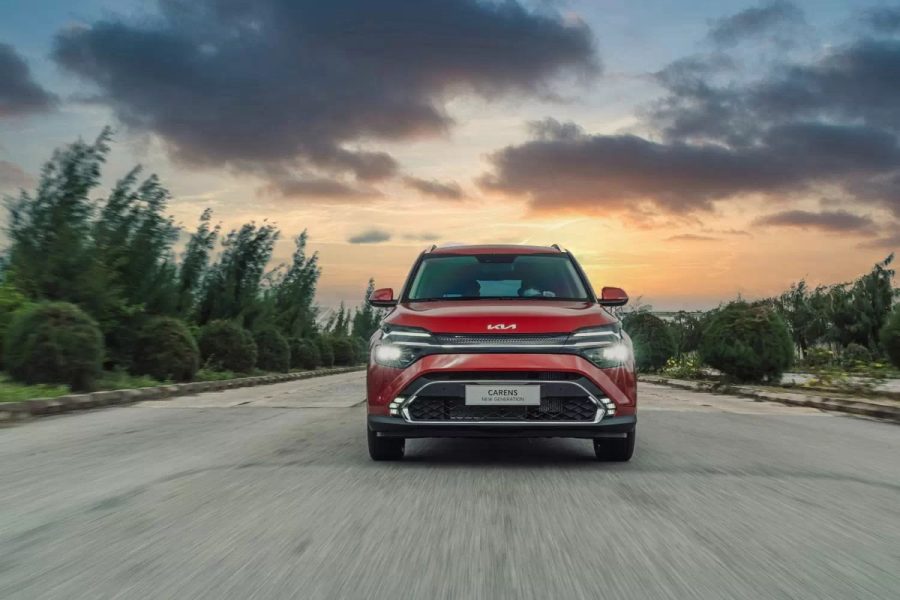 Kia Carens màu đỏ trên đường lúc hoàng hôn