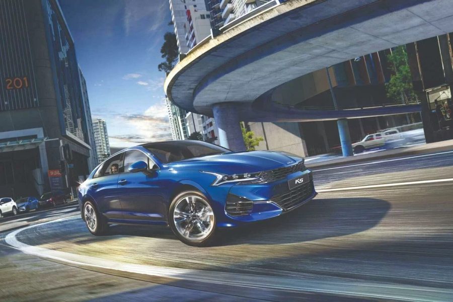 Kia K5 màu xanh chạy trên đường phố